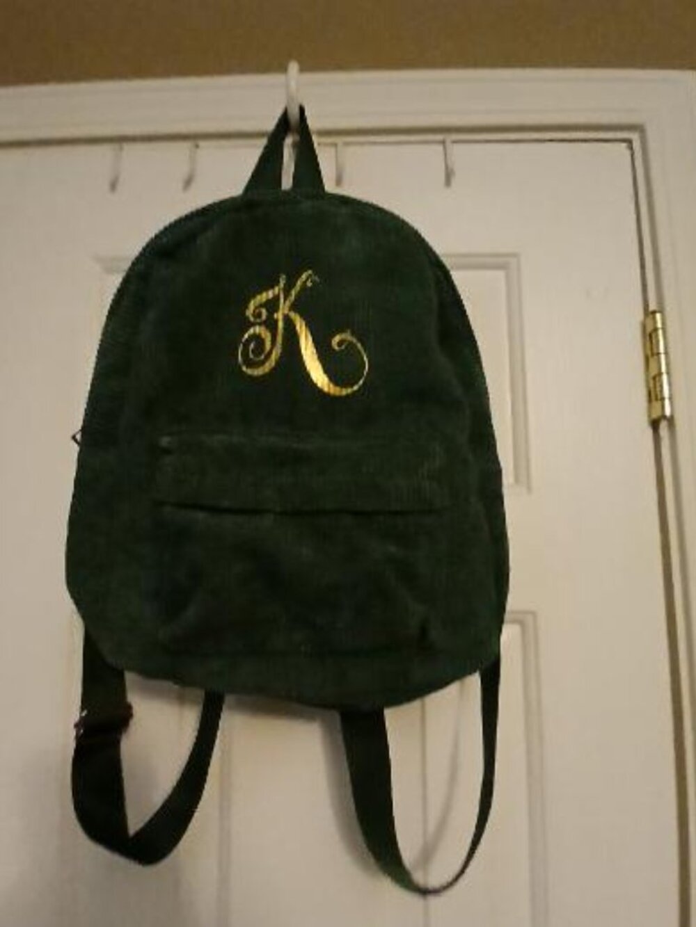 Green corduroy backpack with gold "K"